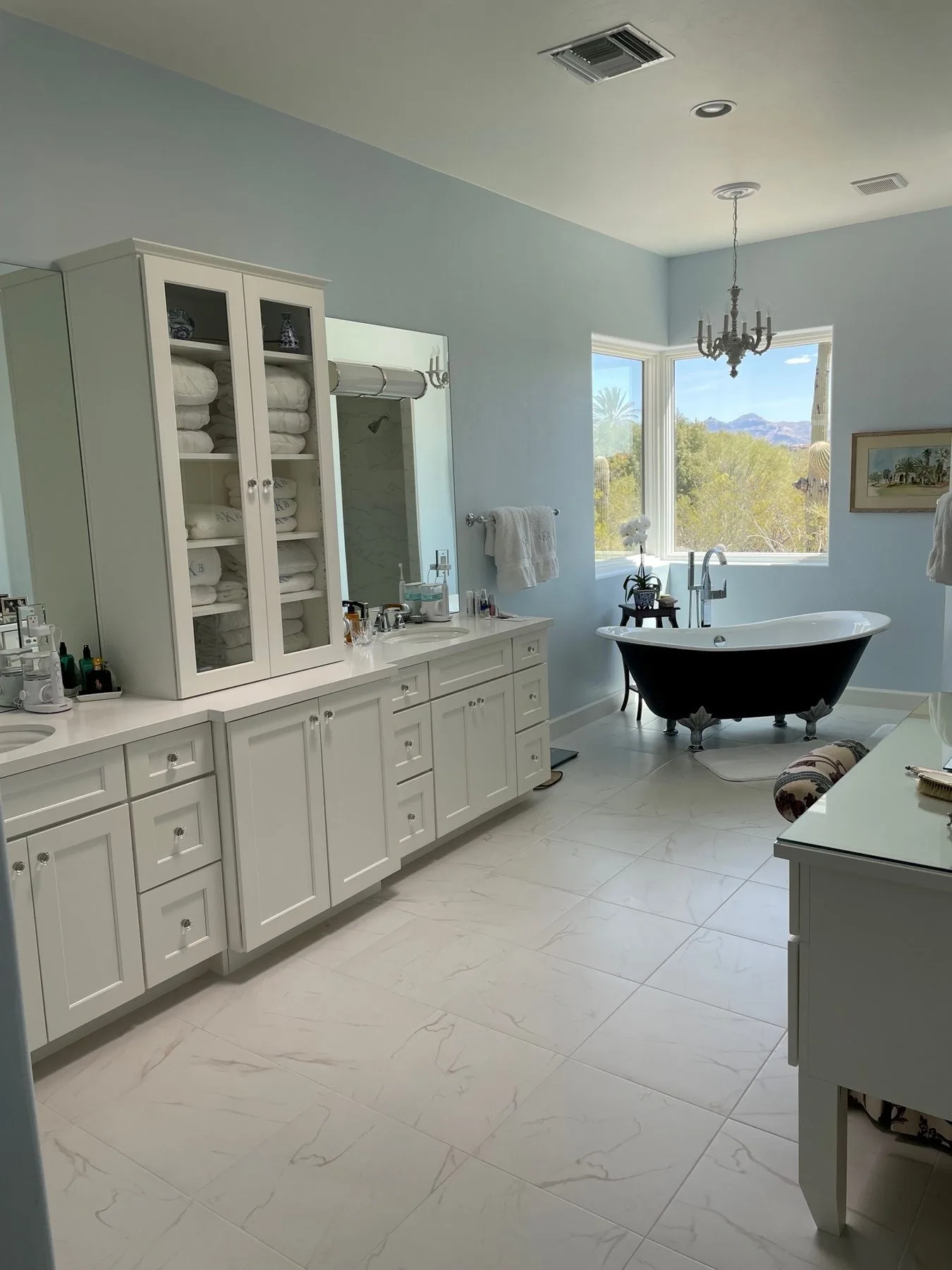 Primary bathroom remodel with white vanity cabinetry, a linen tower and a freestanding tub