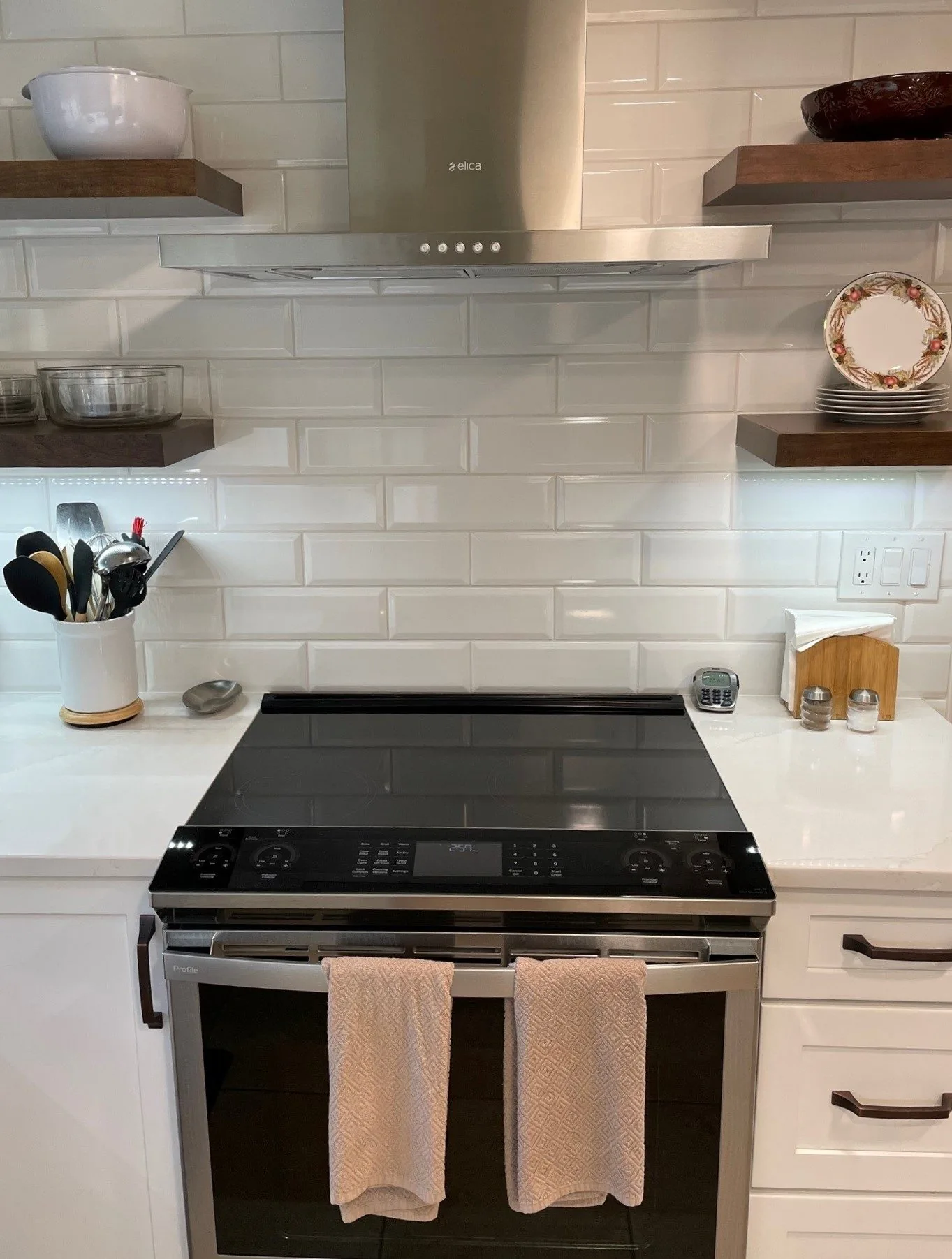 Kitchen range wall with a white subway tile backsplash and floating wood shelves