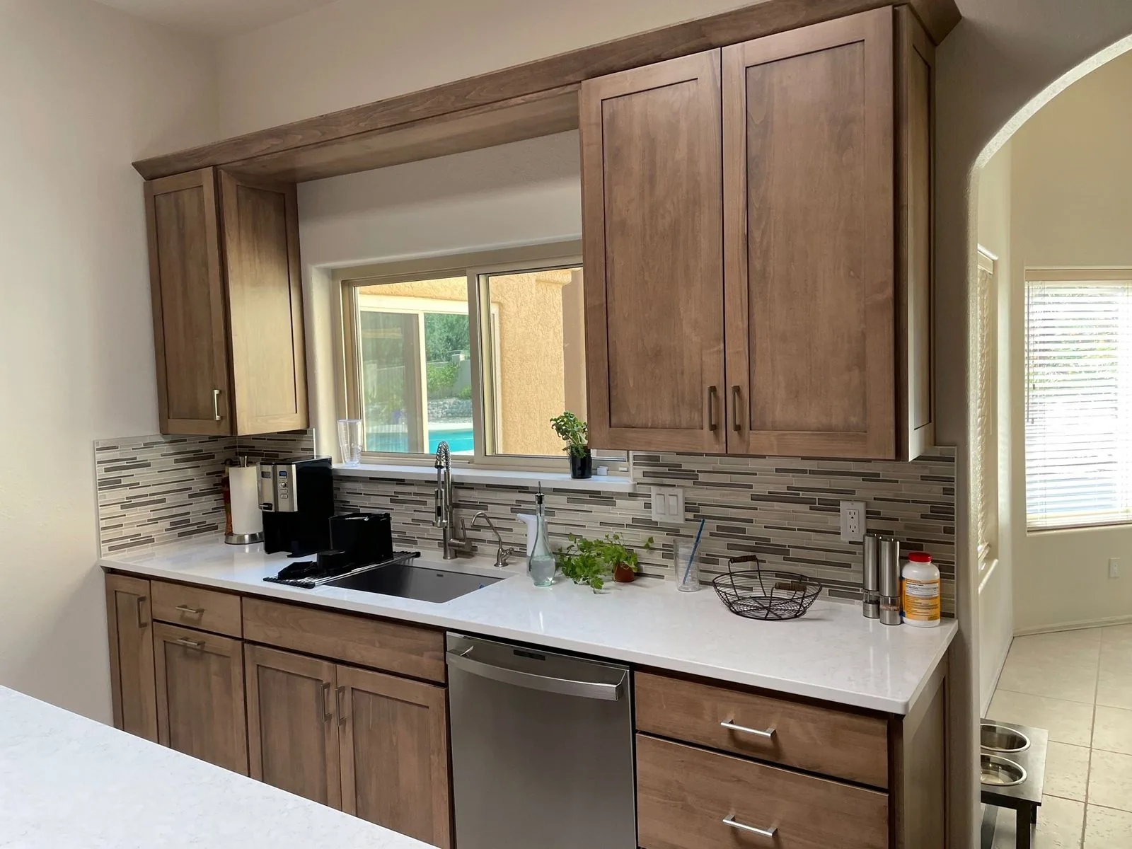 Stained shaker cabinetry with white quartz counters and a glass mosaic backsplash