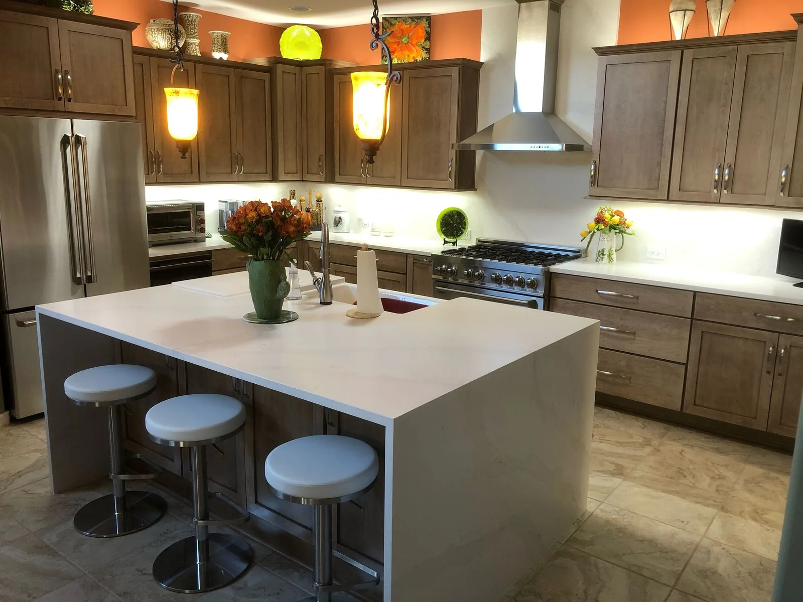 Kitchen remodel with a waterfall quartz island, stained cabinetry and a gas range